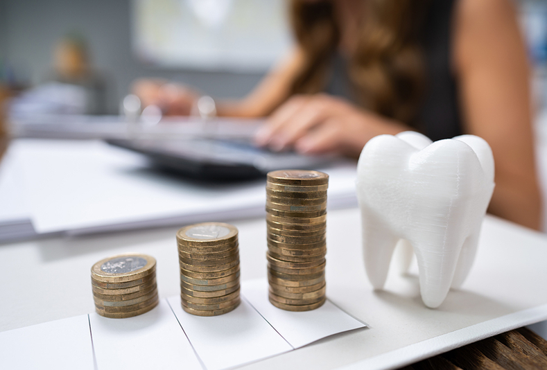 Modellino a forma di dente e monete impilate