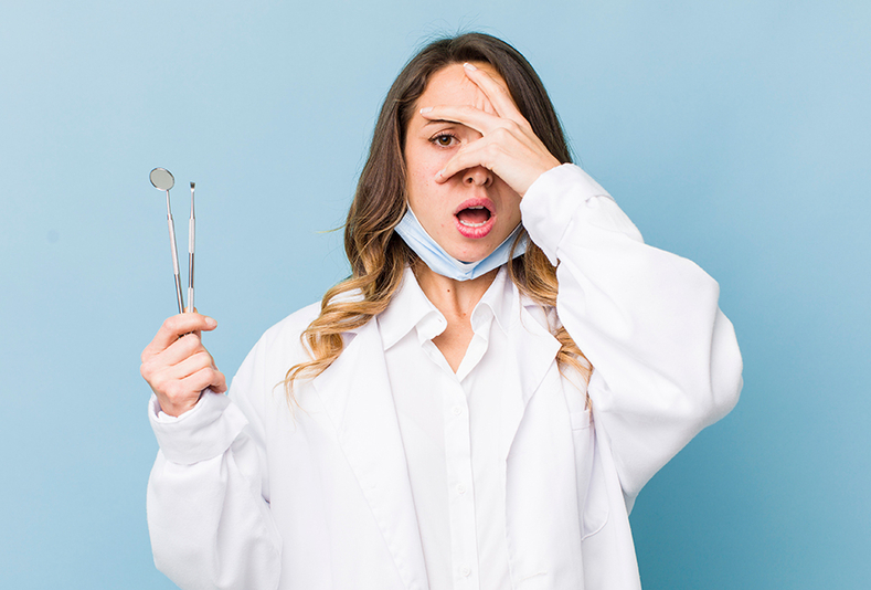 Dentista che si copre il viso con la mano destra