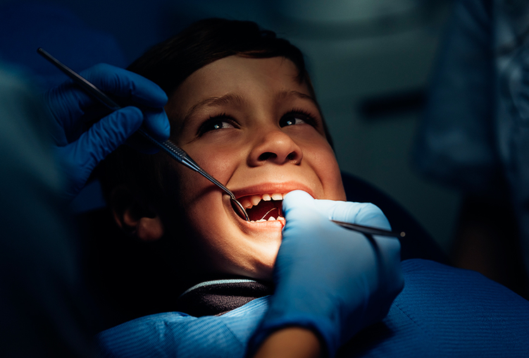 Bambino dal dentista a cui viene effettuata l'estrazione di denti