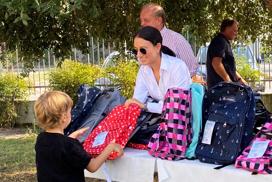 Donna che passa lo zaino ad un bel bambino biondo che inizia la scuola